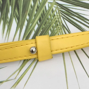 Dettaglio della tracolla in pelle giallo acceso con cuciture fini e rivetti in metallo argento