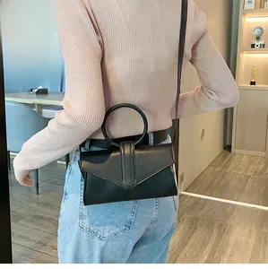 Moderna borsa a busta nera con grande manico rotondo indossata da una persona