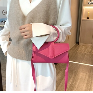 Dettaglio della borsa in pelle rosa fucsia con manico circolare e doppia patta a V