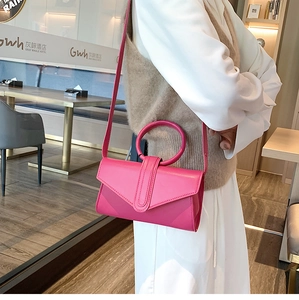 Dettaglio macro della borsa a busta rosa con manico circolare e tracolla sottile