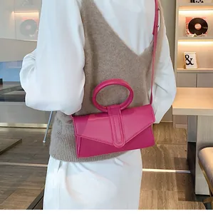 Dettaglio della borsa a busta in pelle rosa rossa con manico circolare e tracolla