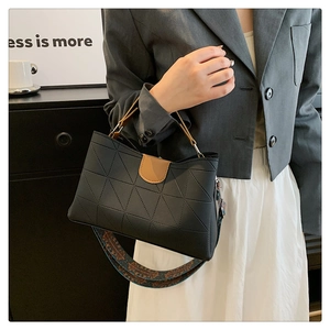 Detail of black tote bag with geometric texture, colorful strap and brown handles