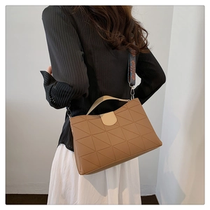 Close-up of brown tote bag with geometric quilting and stylish wide printed strap