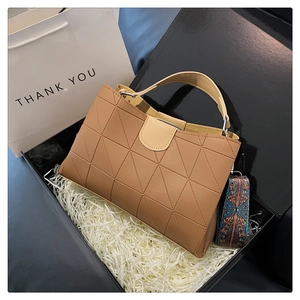 Detail of tan geometric patchwork tote bag with ethnic pattern strap in a gift box