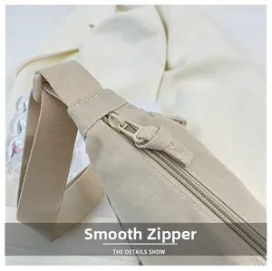 Détail de la fermeture éclair fluide sur un sac bandoulière en nylon beige de forme croissant