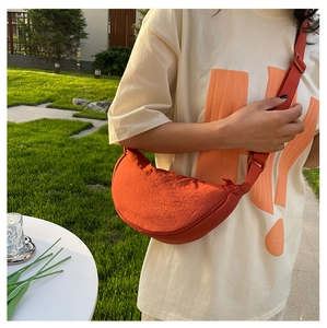 Détail d'un sac bandoulière orange en forme de croissant avec sangle réglable en extérieur
