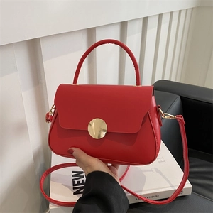 Vintage red leather crossbody bag with a large gold buckle on white prop books