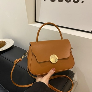 Vintage brown leather crossbody bag with circular gold magnetic clasp and adjustable strap