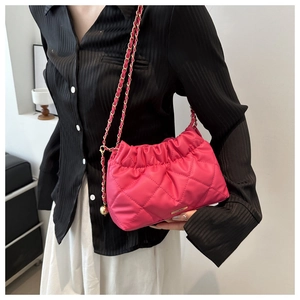 Detail of fuchsia quilted bucket bag featuring elegant gold chain strap and stitching