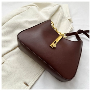 Détail du sac vintage en cuir marron avec fermoir métallique doré et bandoulière chaîne