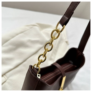 Détail du sac bandoulière en cuir marron avec chaîne dorée et fermeture à glissière