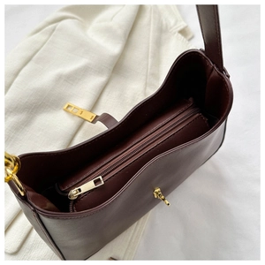 Détail du sac sous le bras marron montrant le compartiment intérieur zippé et les ferrures