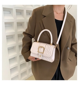Borsa a tracolla trapuntata beige chic con dettagli dorati indossata con blazer marrone