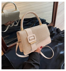Detail of glittery fabric texture and gold metal buckle on a beige PU crossbody bag
