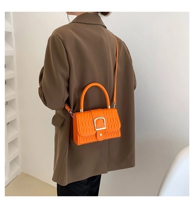 Dettaglio borsa quadrata arancione goffrata con fibbia a U dorata e texture trapuntata