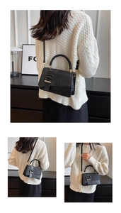 Detail of elegant black PU crossbody bag with glitter texture and gold buckle accents