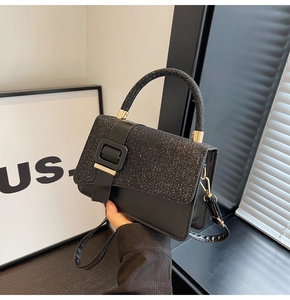 Detail of black sequined square handbag with leather strap and top handle design
