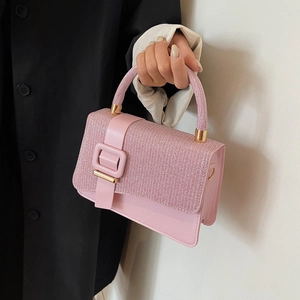 Detailed view of pink glitter clutch handbag with gold-tone hardware held by model