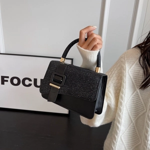 Detail of black PU leather and glitter flap bag with golden buckle and textured finish
