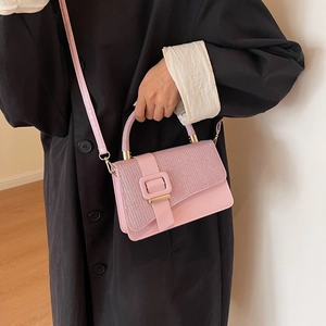 Detail of pink crossbody bag with rhinestone flap and gold hardware on black coat