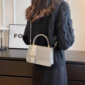 Detail of glittery silver flap and square buckle on a premium white PU crossbody bag