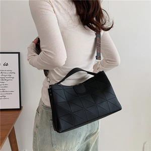 Black geometric tote bag with ethnic print wide strap shown on a model against white wall