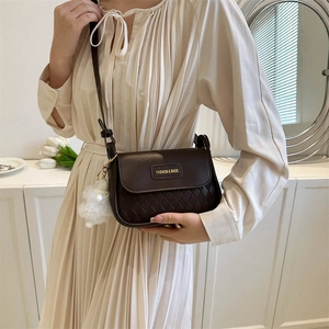 Dark brown quilted crossbody bag with golden plaque and plush charm accessory