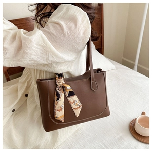 Detail of a brown PU leather tote bag featuring white stitching and a geometric silk scarf