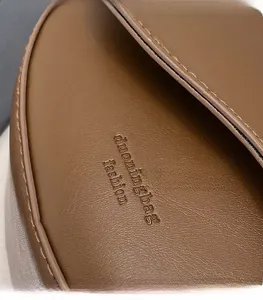 Close-up of brown faux leather handbag showing precise stitching and embossed brand logo
