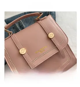Close-up of pink faux leather bag featuring golden buckles and TidalDryness lettering