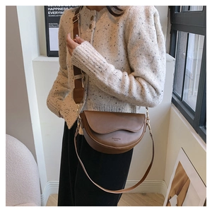 Detail of dark brown saddle bag featuring wave-edge flap and contrast stitching