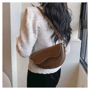 Close-up of brown PU leather crescent shoulder bag with stitching and gold hardware detail