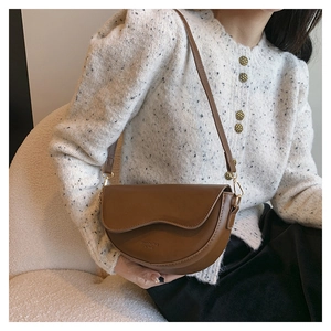 Close-up of brown leather saddle bag with wavy flap detail and golden hardware