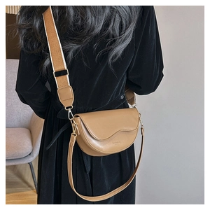 Close-up of brown crescent saddle bag featuring a wavy flap and stylish wide woven strap