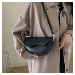Detail of a black matte saddle bag with wide strap and subtle gold hardware