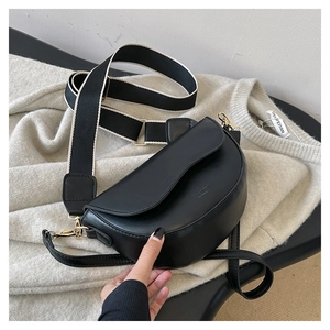 Detail view of black saddle bag with stylish wide woven strap and gold hardware accents
