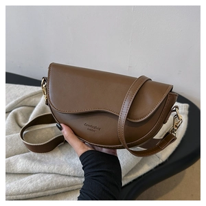 Minimalist brown saddle shoulder bag with wide strap and gold hardware accents