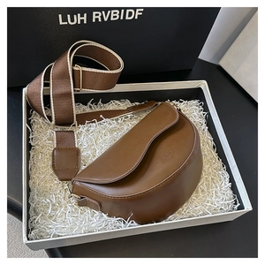 Brown leather saddle bag with wide strap and gold lettering details in a gift box