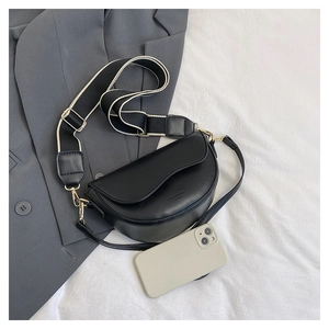 Detail of black saddle bag with adjustable wide woven strap and gold-tone hardware on blazer