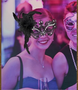 Detail of black lace masquerade mask with ornate feathers, floral decor and rhinestones