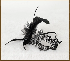 Detailed view of black metal filigree mask with feathers and rhinestones for masquerade