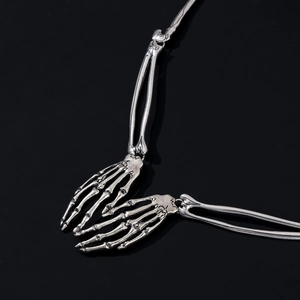 Macro detail of gothic punk silver alloy skeleton hand necklace with vintage bone texture