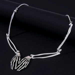 Detailed view of silver skull hand skeletal pendant on black cylindrical stand