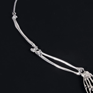 Macro detail of silver skeleton hand necklace with vintage black oxidation texture