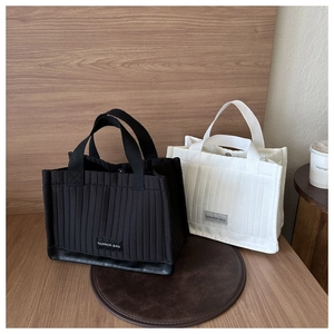 Close-up of quilted vertical striped tote bags in black and white with fashion labels