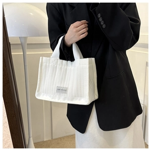 Detail of white quilted canvas tote bag featuring a Fashion Bag label and vertical stitching