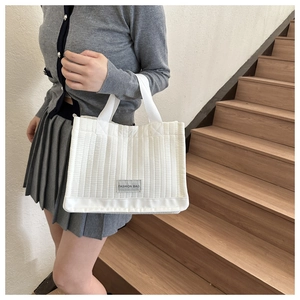 Close-up of white quilted tote bag featuring a Fashion Bag label and ribbed textile texture