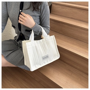 Detail shot of white quilted tote bag texture and fashion label on soft cotton fabric