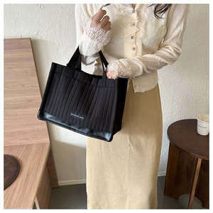 Close-up of black quilted tote bag featuring vertical stitching and Fashion Bag label