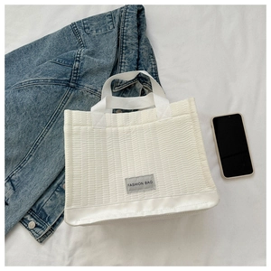 Detailed view of white quilted tote bag with horizontal stitching and Fashion Bag label